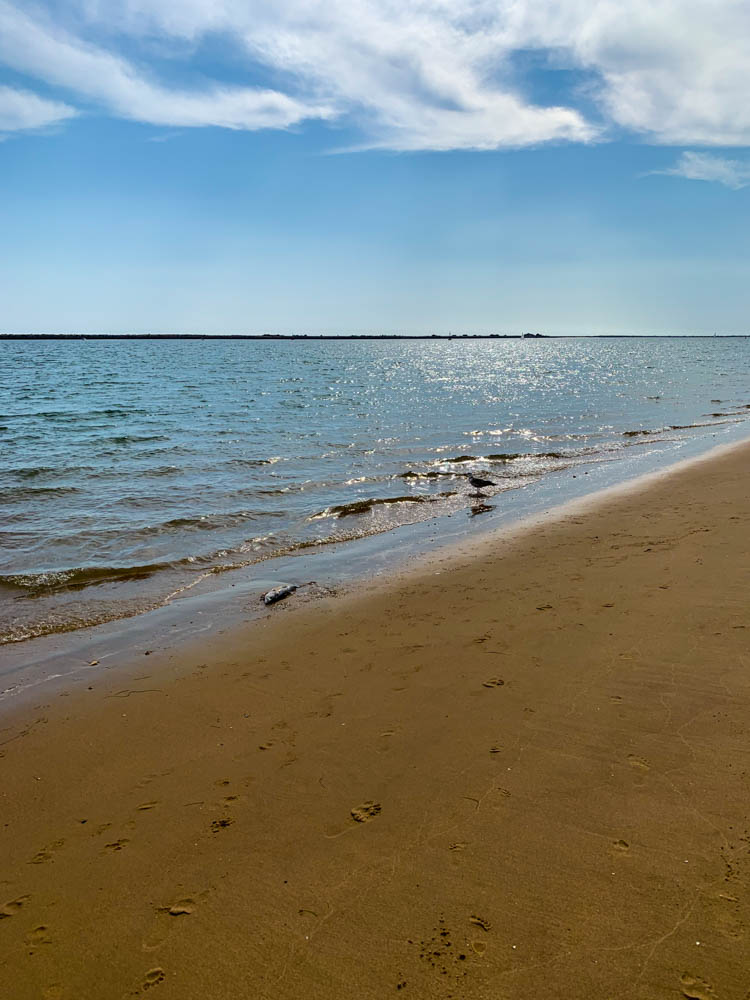 Atlantik und Strand bei Huelva. Der Himmel ist blau, das Meer ruhig und der Sand hellbraun