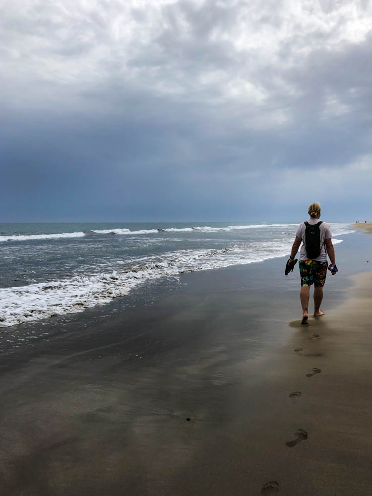 Julian läuft barfüßig am Strand von Maspalomas. Der Himmel ist dunkel und ergibt ein mystisches Bild
