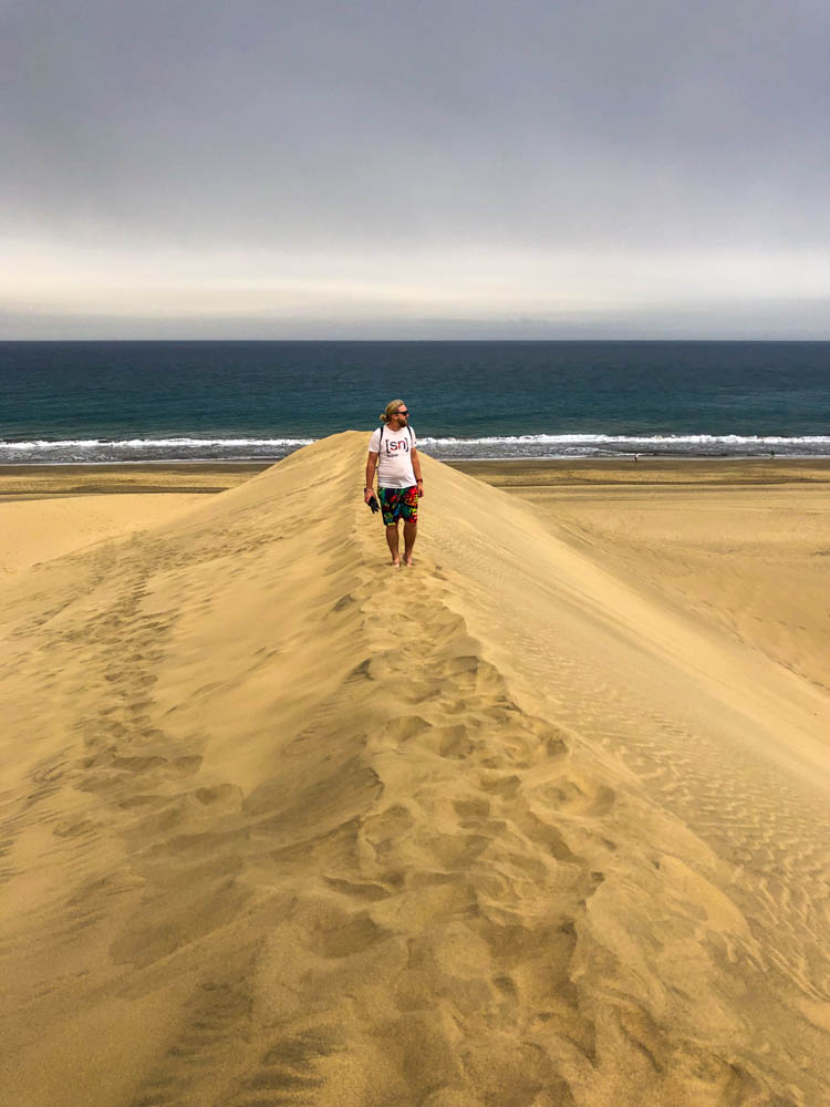 Julian läuft auf einem Grat in den Dünen von Maspalomas auf Gran Canaria. Hinter ihm ist der Ozean, ansonsten ist nur Sand zu sehen.