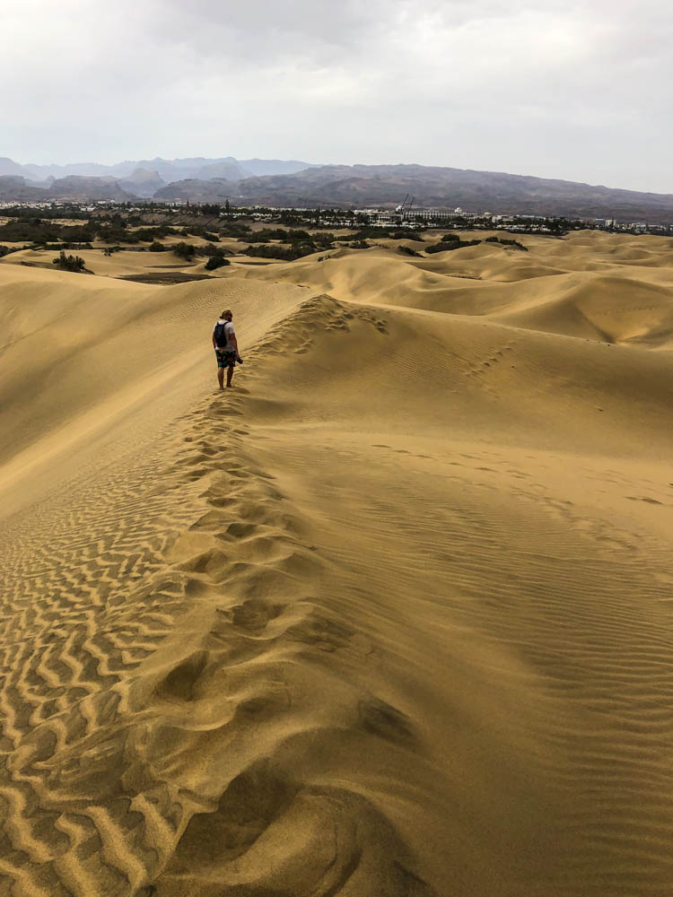 Julian in den Dünen von Maspalomas Gran Canaria. Im Hintergrund sind ein paar Hügel zu sehen, ansonsten überall Sand