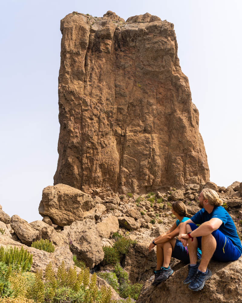 Melanie und Julian sitzen vor dem Roque Nublo auf Gran Canaria.