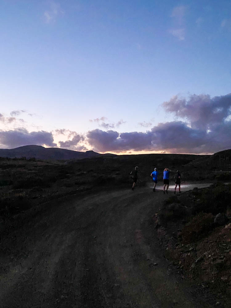 Laufgruppe abends beim joggen. Die Läufer müssen Stirnlampen benutzen, da es gerade dunkel wird. Fuerteventura joggend entdecken