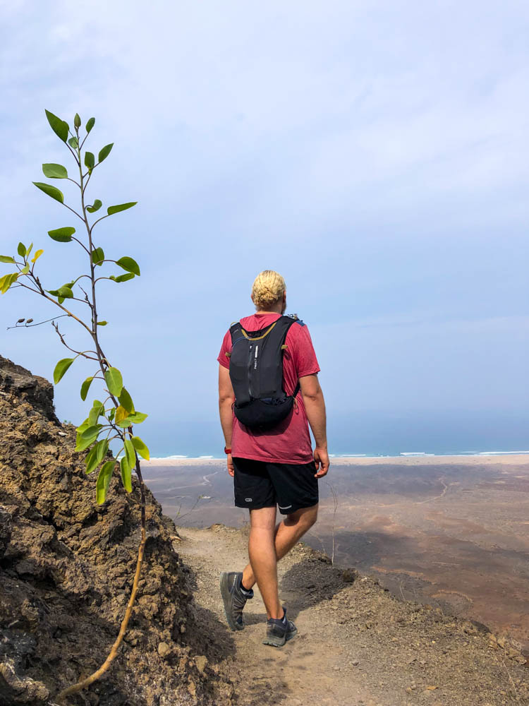 Julian bei Wanderung nach Cofete. Das Ziel, der Sandstrand, ist von der Höhe zu sehen. Der Himmel ist bewölkt. Wandernd schöne Ecken auf Fuerteventura entdecken.