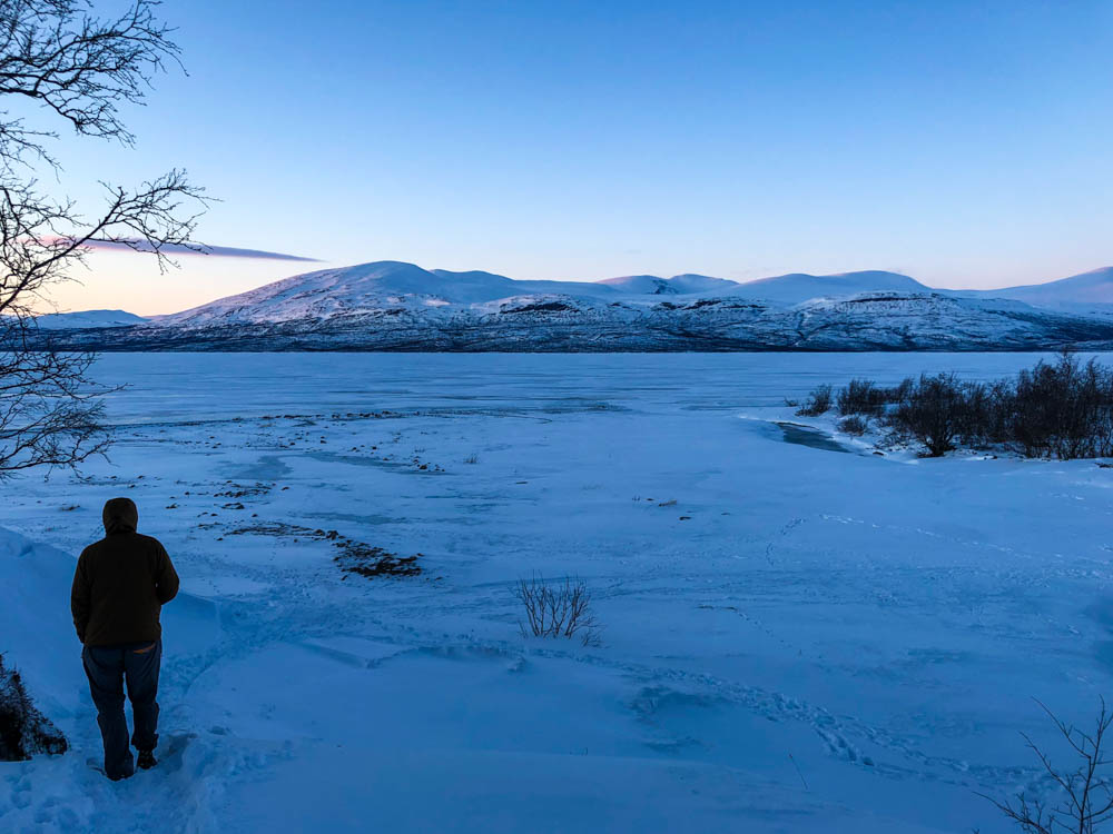 Julian auf dem Weg zum See Torneträsk im Abisko Nationalpark. Die Sonne geht gerade unter. Es liegt überall Schnee