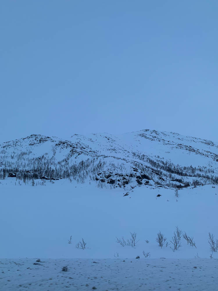 Bergkulisse Norwegen - der Himmel ist weiß, der Berg zeigt schwarze Konturen, ist ansonsten auch weiß und davor liegt Schnee.