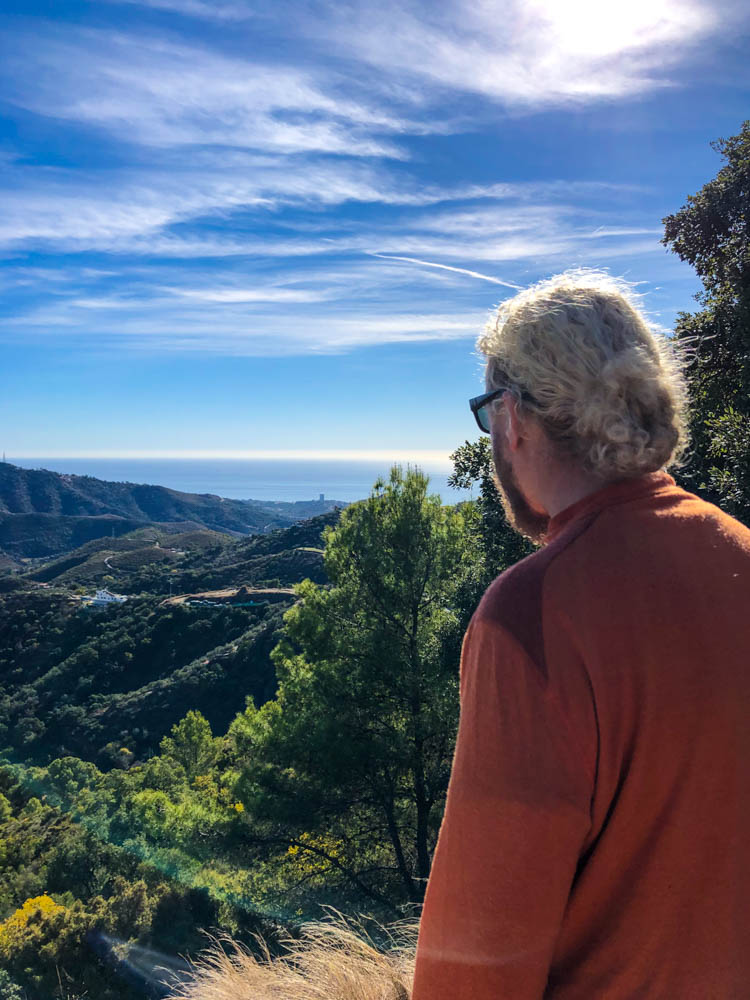 Julian blickt von einem Aussichtspunkt über die Hügellandschaft in Andalusien. In der Ferne ist das Mittelmeer zu sehen. Rückfahrt über Spanien durchs Landesinnere