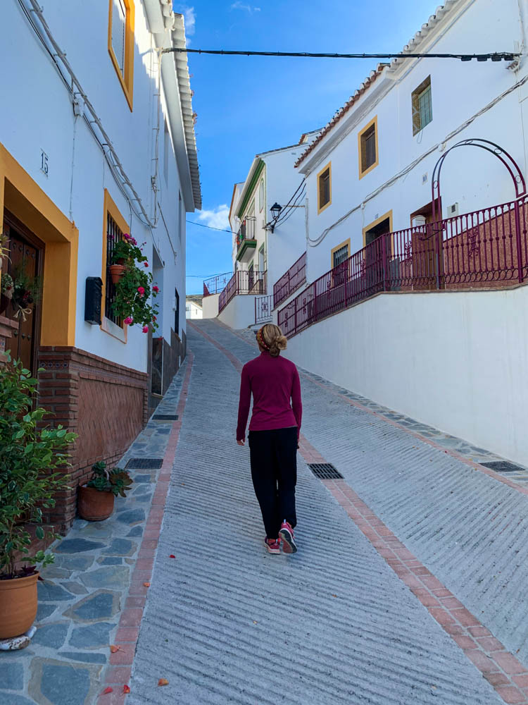 Melanie läuft durch eine schöne Gasse in einem Dorf im Landesinneren von Andalusien.