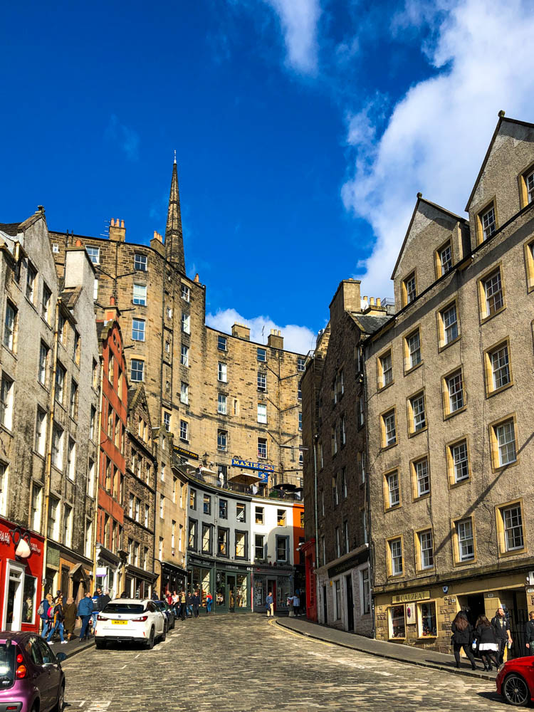 Blick in Gasse mit hohen, alten Häusern in Edinburgh. Der Himmel ist strahlend blau.