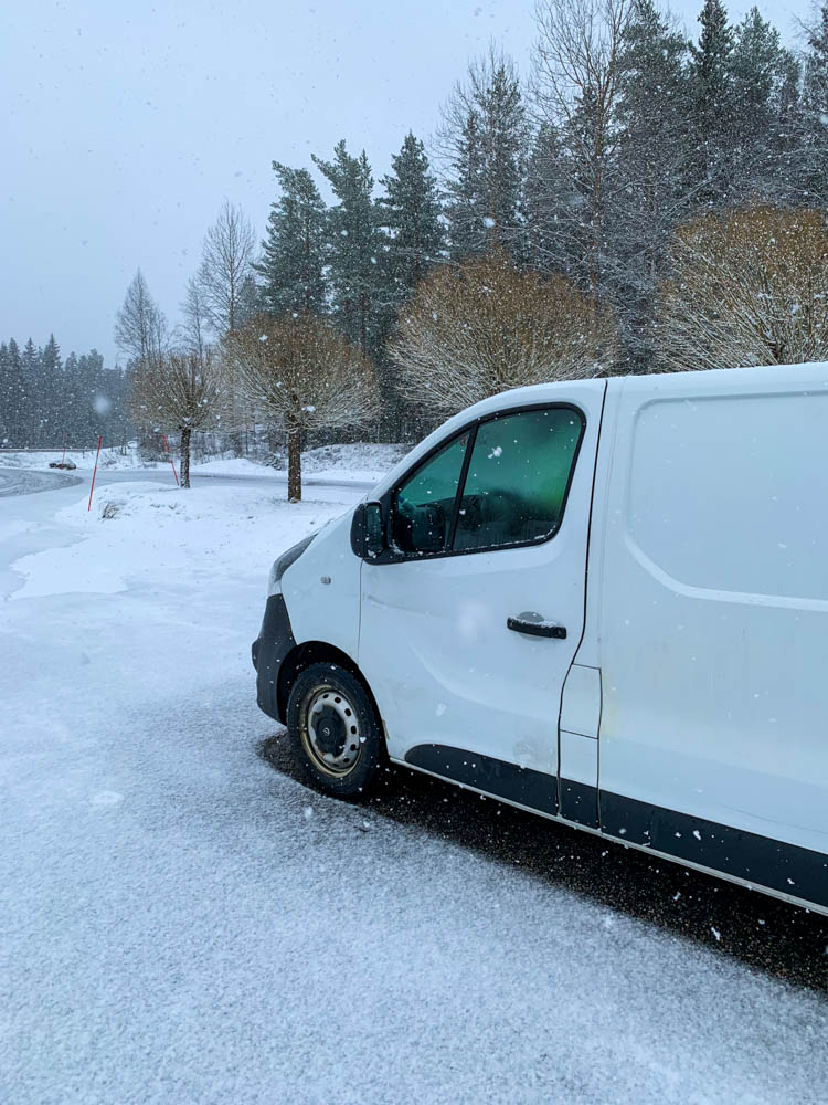 Van Vivaldi auf einem Parkplatz in Schweden. Es schneit, überall liegt Schnee und der Himmel ist sehr bedeckt. Weißer Van in weißer Landschaft