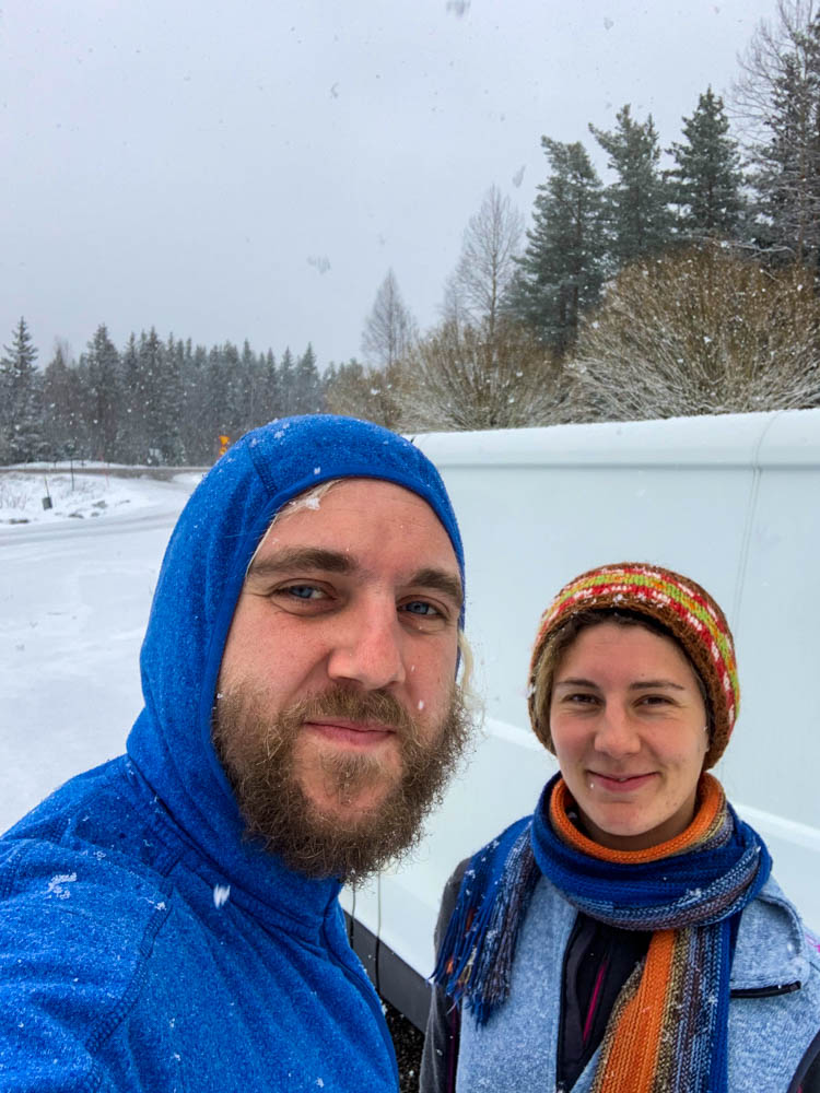 Selfie von Melanie und Julian vor Van Vivaldi auf einem Parkplatz in Schweden. Es schneit auf dem Weg in den hohen Norden