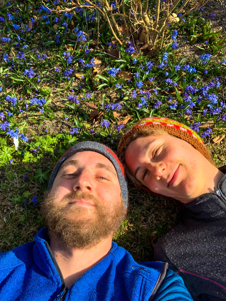 Melanie und Julian liegen in einer Wiese voller Blumen. Selfie - Fahrt in den hohen Norden