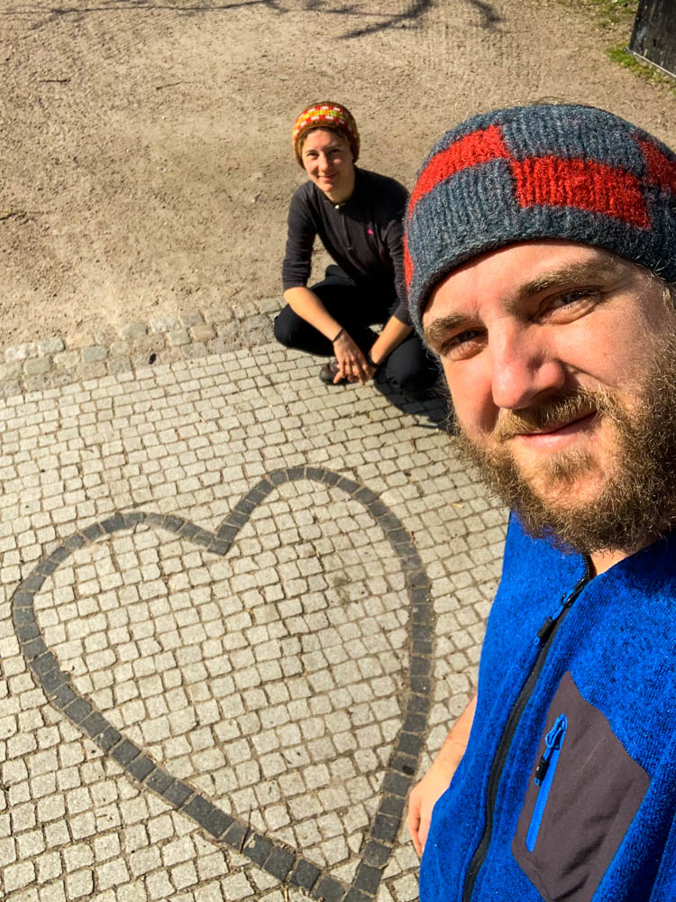 Selfie von Melanie und Julian in Südschweden. Es ist ein Herz aus Pflastersteinen auf dem Boden zu sehen.