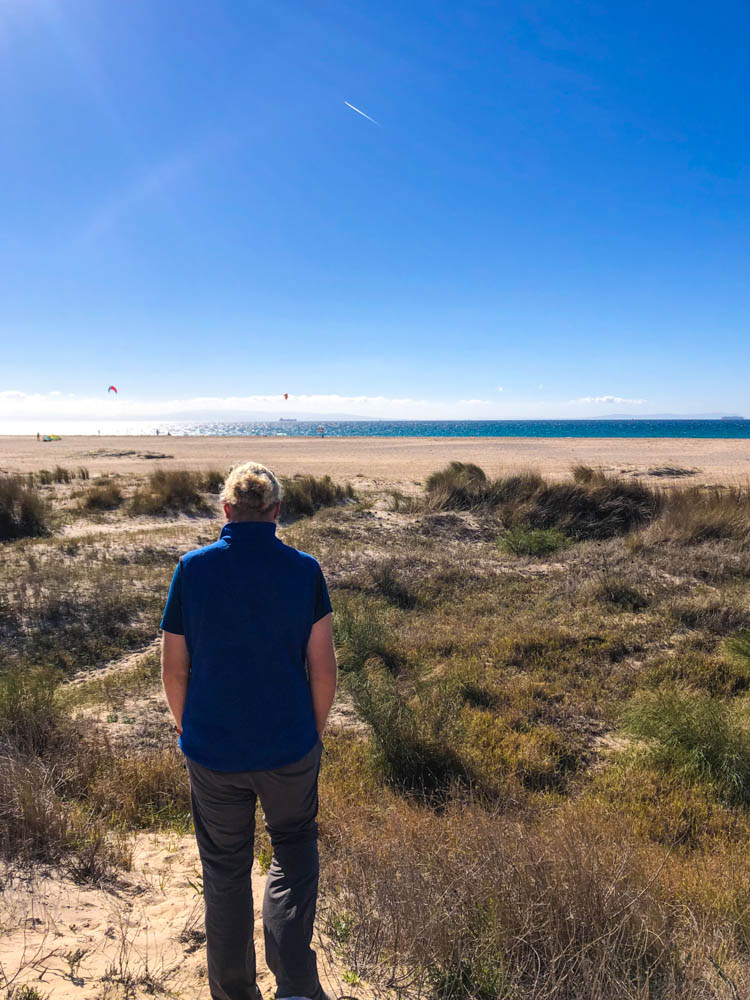 Julian läuft zum Strand, um Kitesurfer im Atlantik zu beobachten. Der Himmel ist kräftig blau.