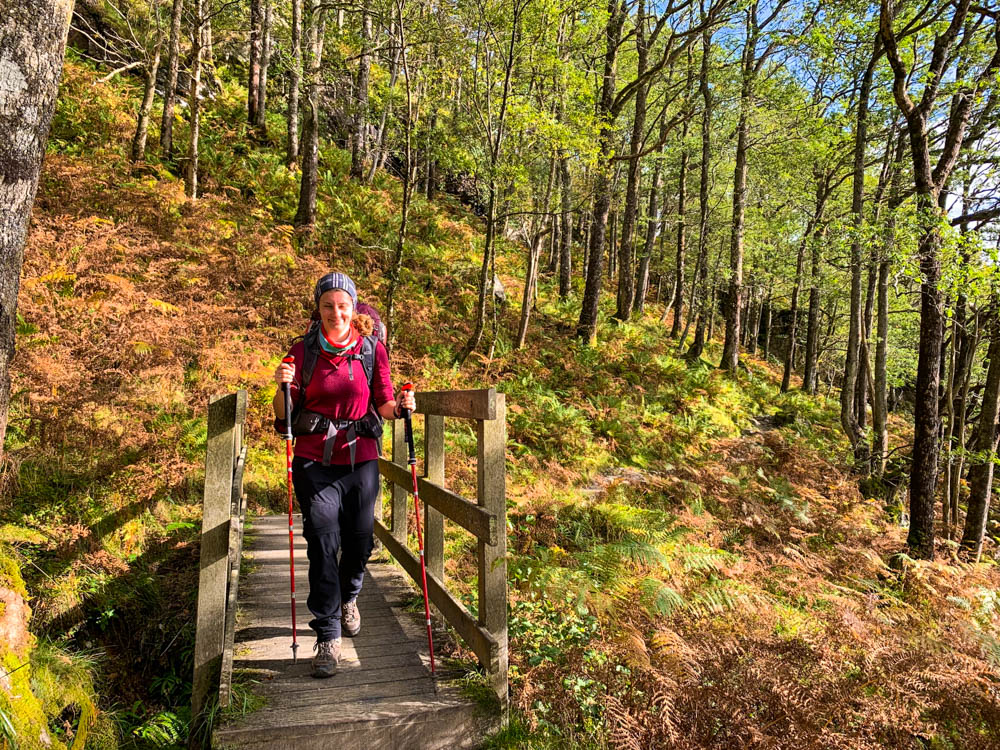 Trekking West Highland Way Schottland - Melanie läuft gerade über eine Brücke in einem Waldstück. Sie hat ein grinsen auf dem Gesicht.
