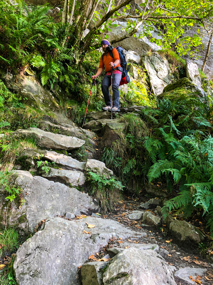 Julian wandert ein steiles Stück auf Steinstufen herab. Trekking West Highland Way Schottland.
