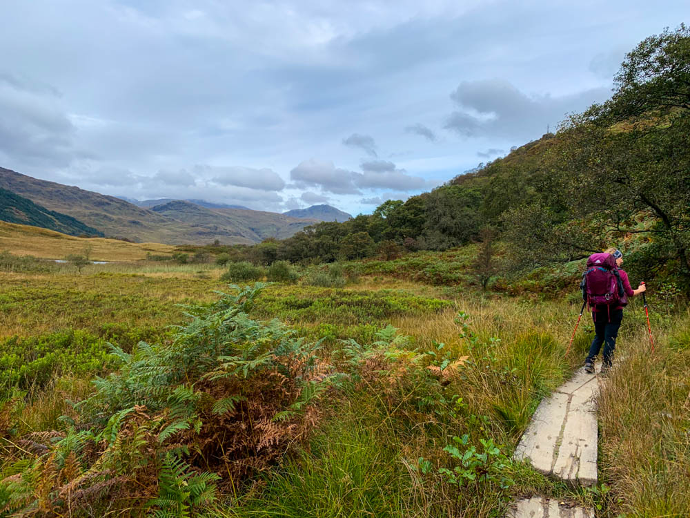 Melanie wandert über einen Holzsteg in einem Moorgebiet. Trekking West Highland Way Schottland