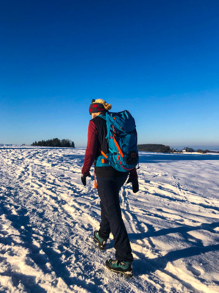 Julian beim Wandern in Kempten in Schneelandschaft. Der Himmel ist kräftig blau