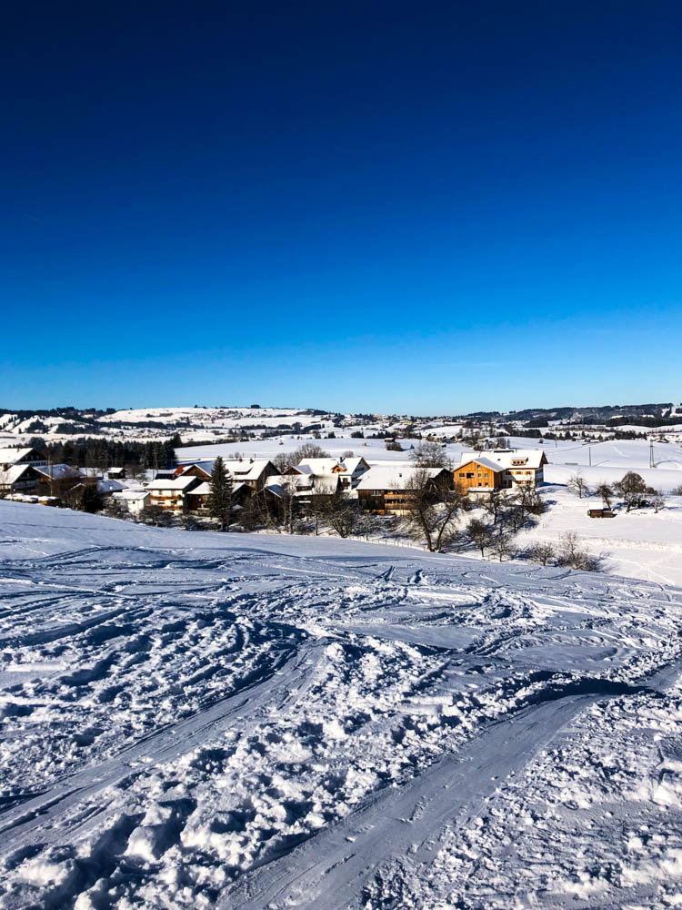 Blick auf Nesselwang in Winterlandschaft. Der Himmel ist kräftig blau.