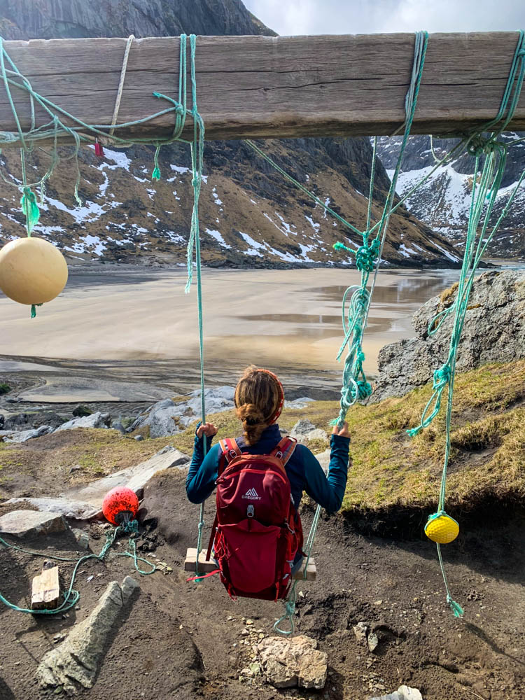 Melanie schaukelt mit Blick auf die Kvalvika Bucht. Lofoten im April - einzigartiges Erlebnis mit leerem Strand und teilweise Schnee