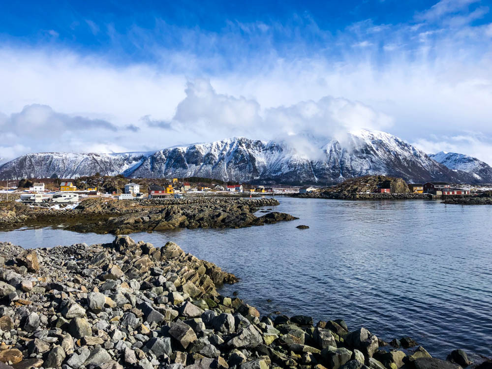 Aufnahme von Laukvik - Lofoten im April. Die Berge sind teilweise noch weiß vom Winter, der Himmel ist leicht bewölkt und der Atlantik schimmert blau.