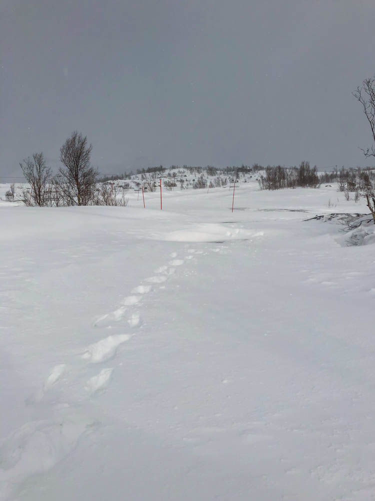 Schneebedeckter Parkplatz Anfang April Nordnorwegen. Es sind nur ein paar Fußspuren im Schnee von Julian zu sehen.