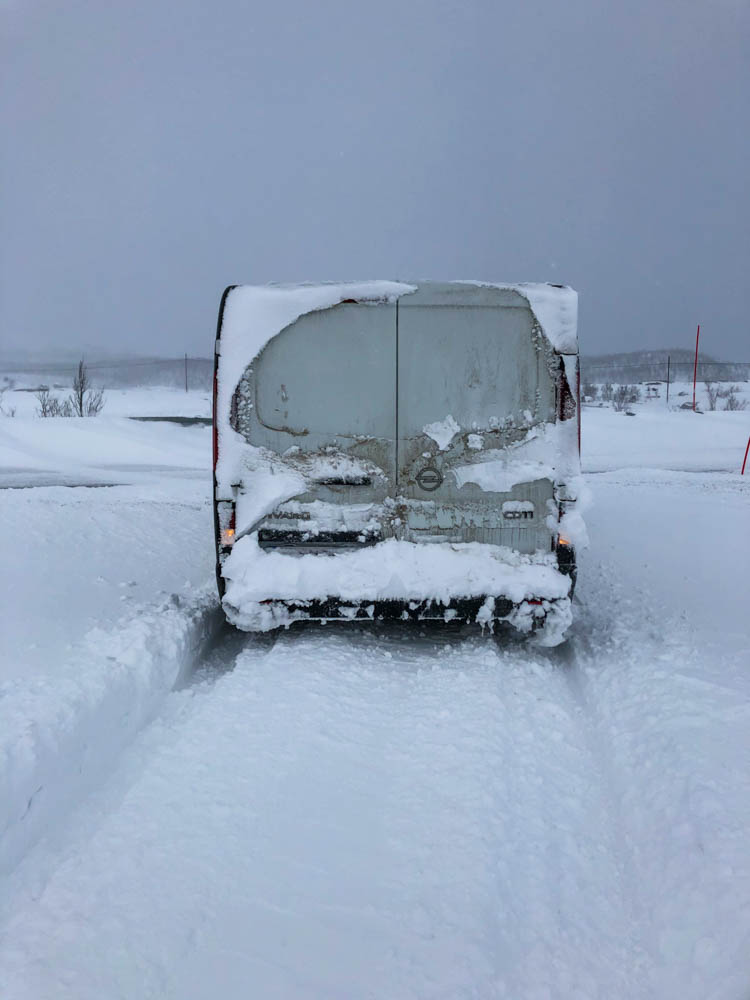 Camper Van Vivaldi fährt von schneebedecktem Parkplatz runter.