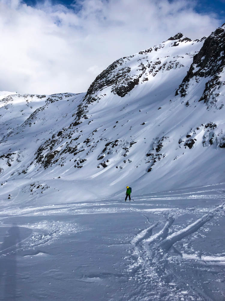 Julian bei der Abfahrt mit seinem Splitboard am Rundfjellet auf den Lofoten im April. Verschneite Berge im Hintergrund