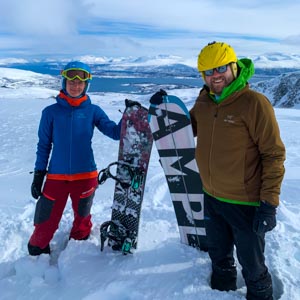 Über Senja nach Tromsö: Splitboardtour in Norwegen. Melanie und Julian grinsen mit ihren Bords, welche im Schnee stecken, in die Kamera.