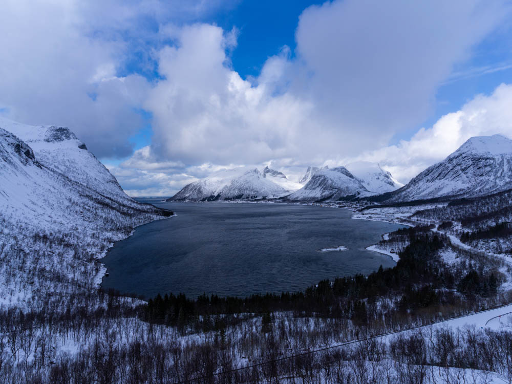 Verschneite Berglandschaft bei Senja. Blick von Anhöhe auf Tal mit Fjord