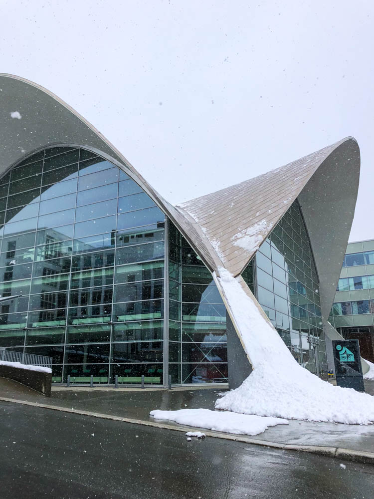 Es ist eine Schneelawine vom Dach der Bibliothek in Tromsö heruntergerutscht und liegt vor dem Gebäude. Das Dach ist bis nach unten gebaut und bildet so eine Rutsche.