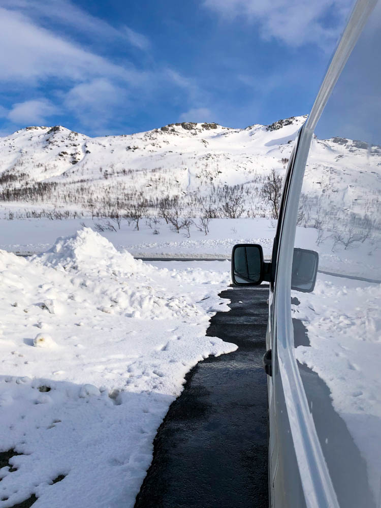 Seitenfront von Van Vivaldi spiegelt Schnee- und Berglandschaft. Der Himmel ist blau, der Rest ist weiß. Über Senja nach Tromsö - Schnee ohne Ende.