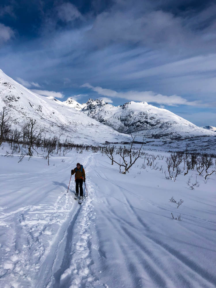 Julian im Aufstieg zum Gipfel Steinskarstinden. Im Hintergrund ist die verschneite Berglandschaft Norwegens zu sehen. Über Senja nach Tromsö - Schnee ohne Ende