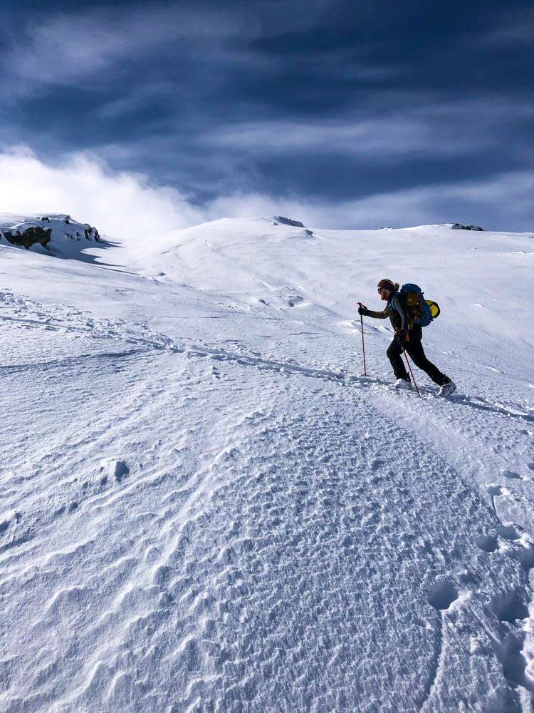 Julian im Aufstieg zum Gipfel Steinskarstinden. Im Hintergrund ist die verschneite Berglandschaft Norwegens zu sehen