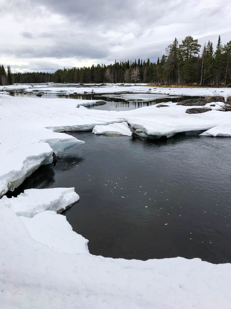 Frühling in Nordschweden - Das Eis auf einem See fängt an zu schmelzen, der Fluss kommt zum Vorschein.