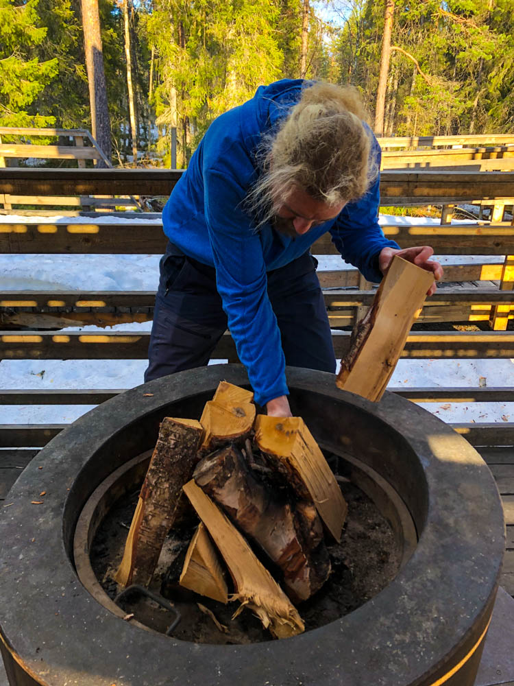 Julian beim Aufbauen eines Lagerfeuers an Lagerstätte von Muddus Nationalpark Nordschweden. Es ist Frühling, es liegt noch ein wenig Schnee, die Sonne scheint jedoch und der Wald ist grün