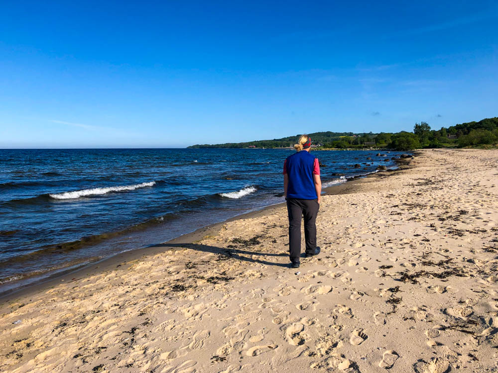 Julian läuft entlang eines Strandes an der Ostsee in Südschweden. Der Himmel ist kräftig blau.