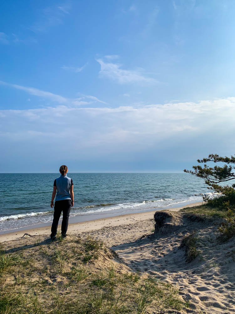 Melanie steht an einer Stranddüne an der Ostsee und blickt aufs Wasser.