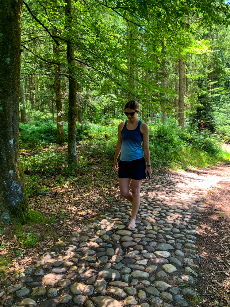 Melanie läuft durch einen Wald im Barfußpark Dornstetten über große Steine.