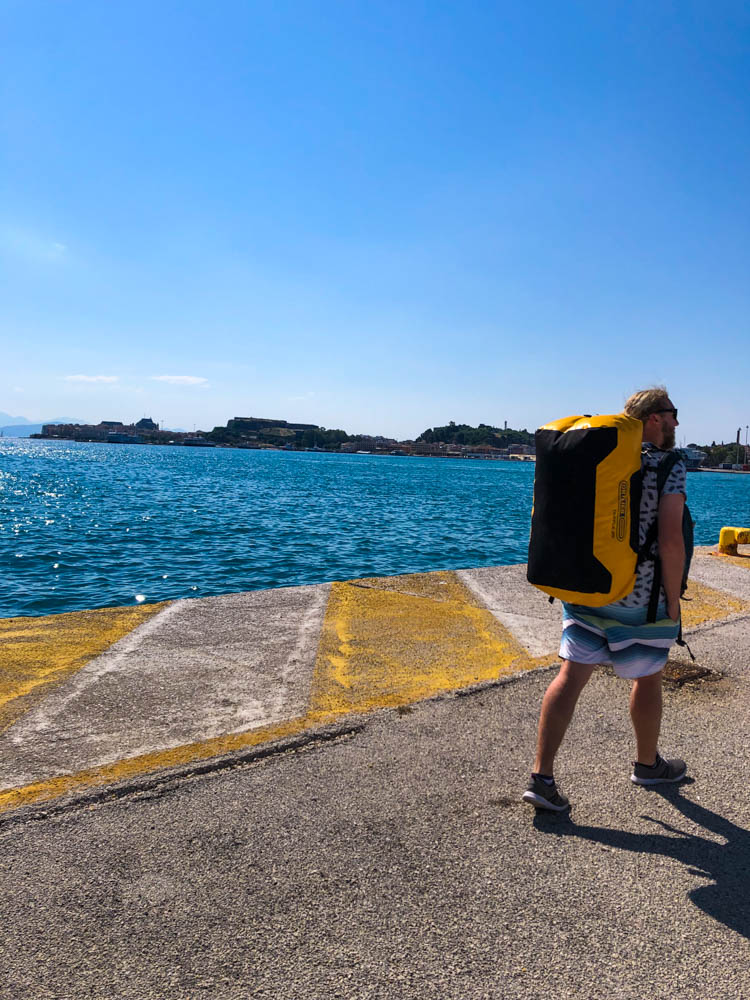 Julian trägt eine große Tasche auf dem Rücken. Spaziergang von AIDA zum Hostel in Korfu