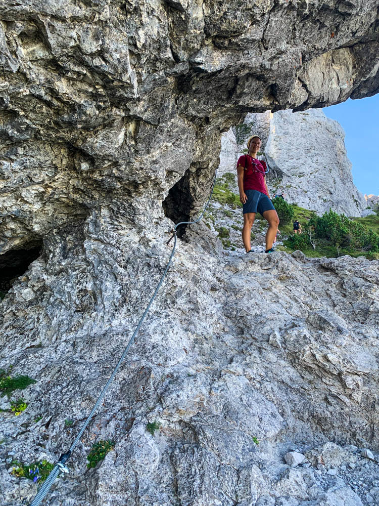 Wanderungen in Liechtenstein. Melanie steht unter einem Felsen im Drei Schwestern Steig und grinst in die Kamera.