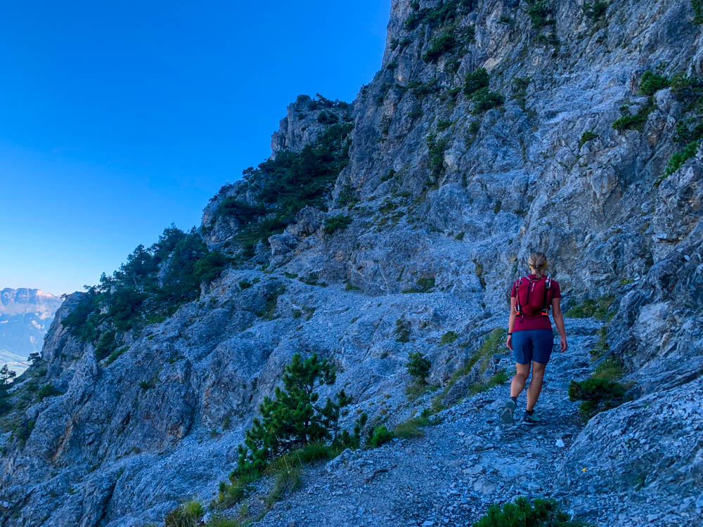 Wanderungen in Liechtenstein. Melanie im Aufstieg auf dem Fürstensteig im felsigen Gelände auf einem schmalen Pfad. Der Himmel ist kräftig blau.