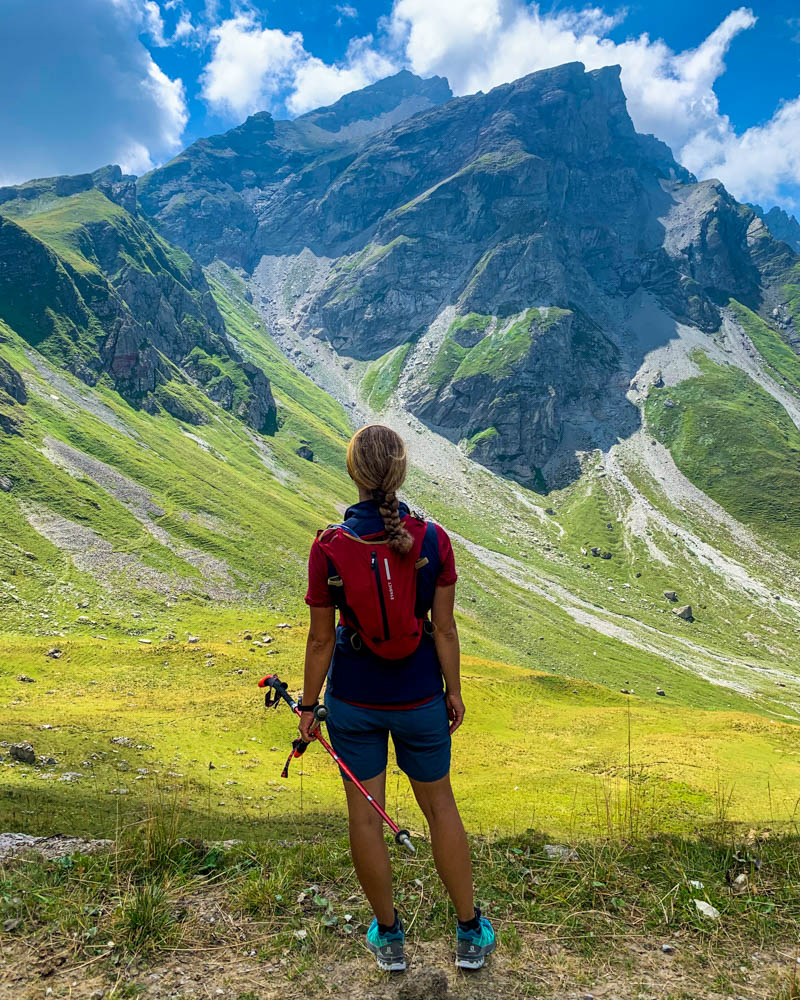 Wanderungen in Liechtenstein. Melanie blickt mit einigen hundert Metern Entfernung auf den Naafkopf, auf welchem sie kurz vorher gestanden ist. Es hängen ein paar Wolken über den Bergen.