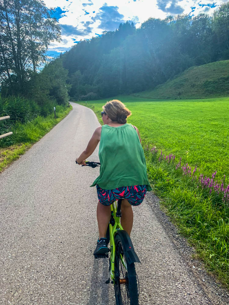 Melanie beim Fahrrad fahren im Allgäu. Grüne Wiesen prägen die Landschaft