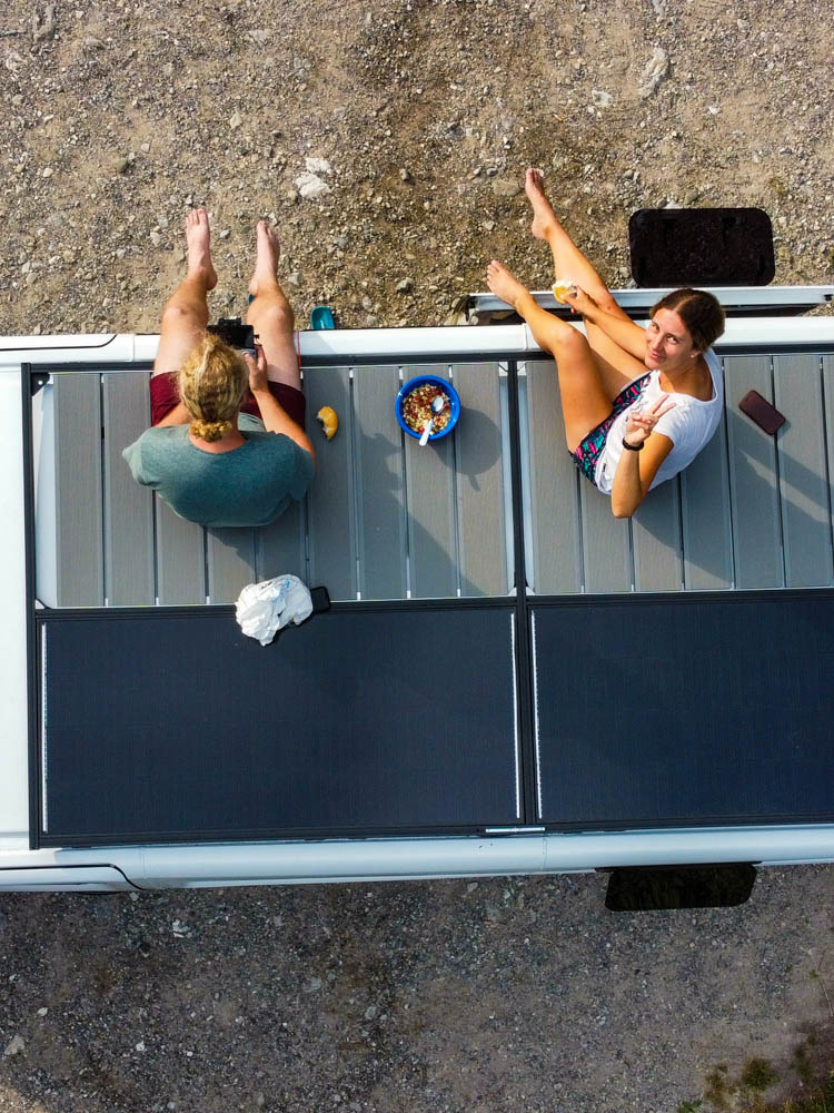 Melanie und Julian sitzen auf der Dachterrasse ihres Van Vivaldi - Camper Vollzeit Reisende
