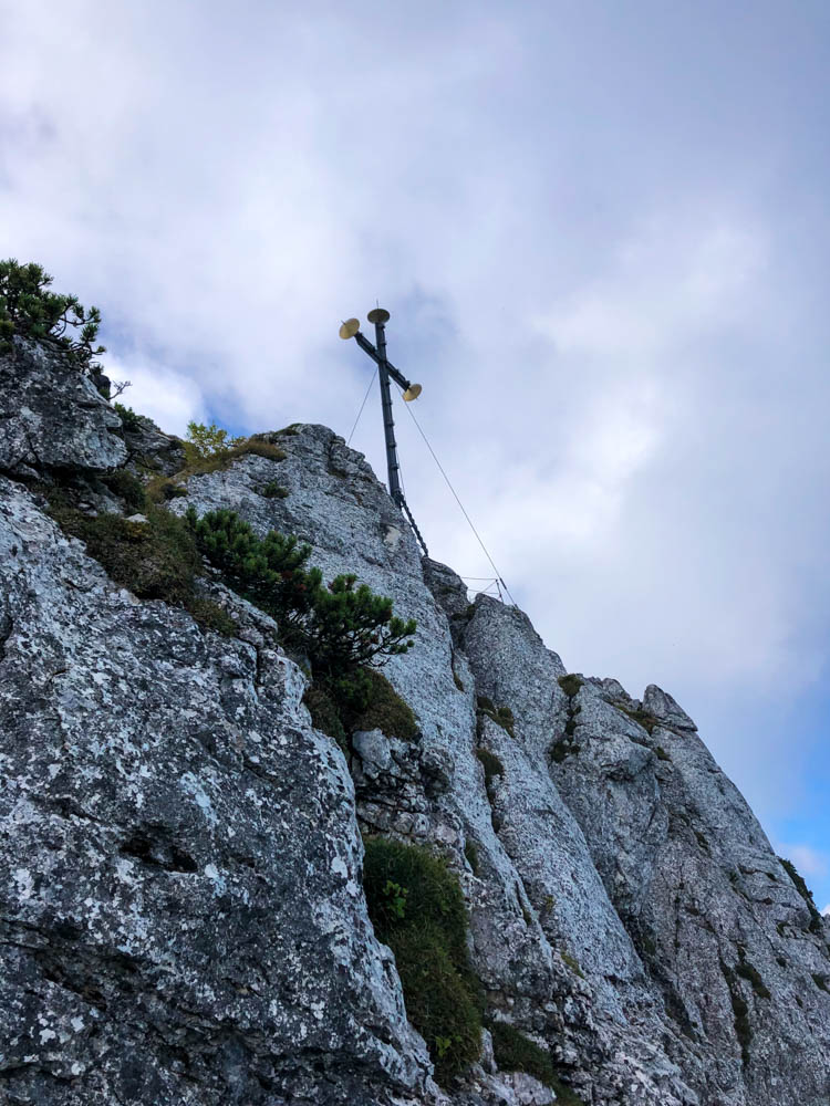 Blick auf Gipfelkreuz der Kampenwand von etwas unterhalb mit Felsen. Ausflugsziele in Bayern