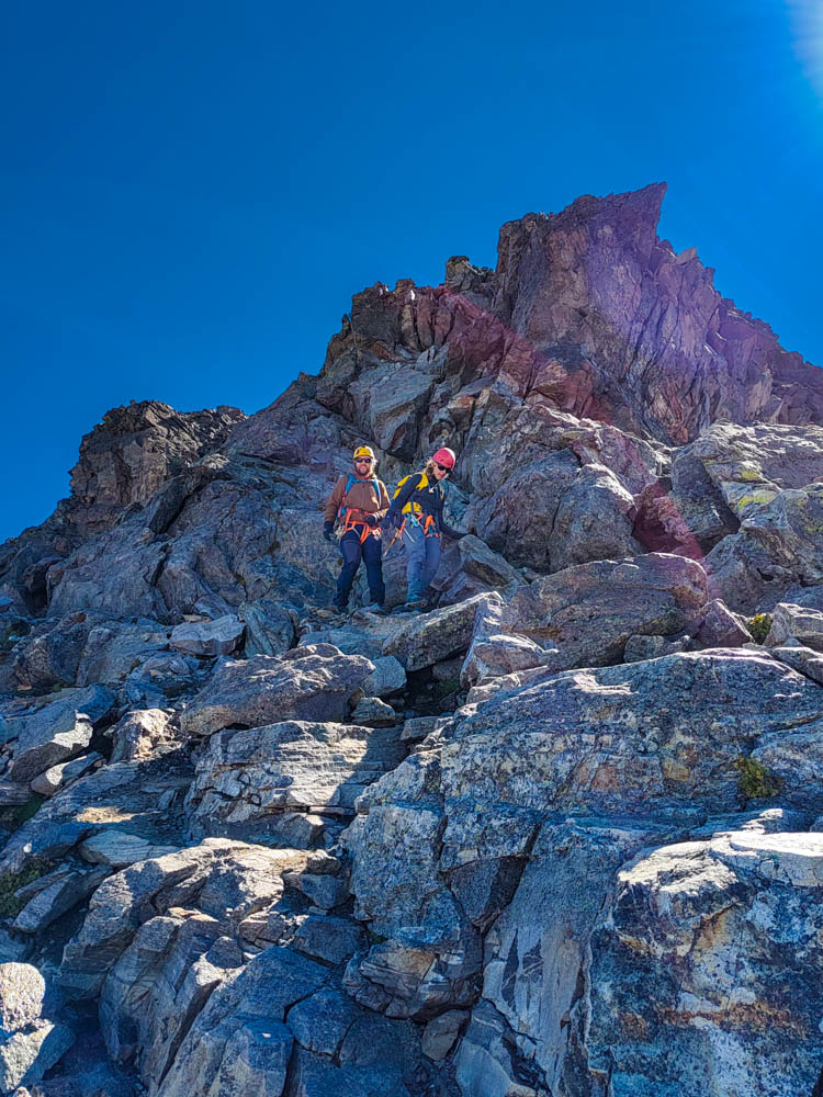 Melanie und Julian im Gipfelabstieg vom Großen Piz Buin im felsigen Gelände. Der Himmel ist kräftig blau.