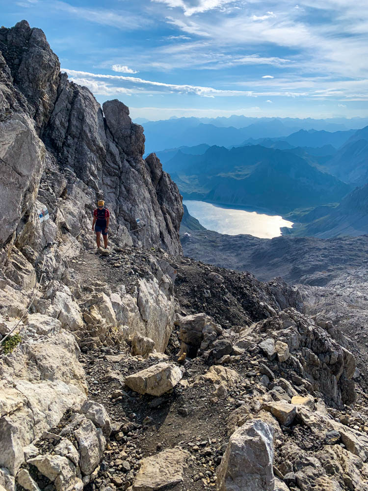 Melanie im Aufstieg zur Schesaplana in Vorarlberg. Im Tal ist der Lünersee zu sehen sowie etliche Bergketten im Brandnertal und Montafon.