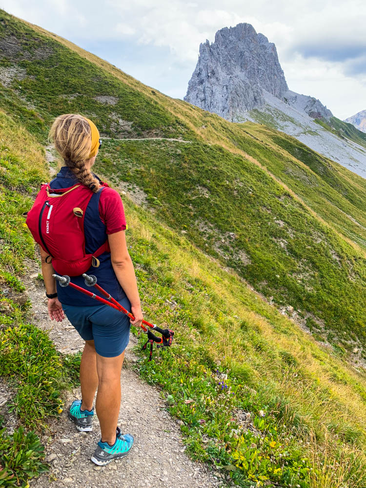 Melanie nach dem Gafalljoch Richtung Lünersee in Vorarlberg. Sie blickt auf eine massive Felswand vor ihr. Saftig grüne Wiesen und die schroffe Felswand