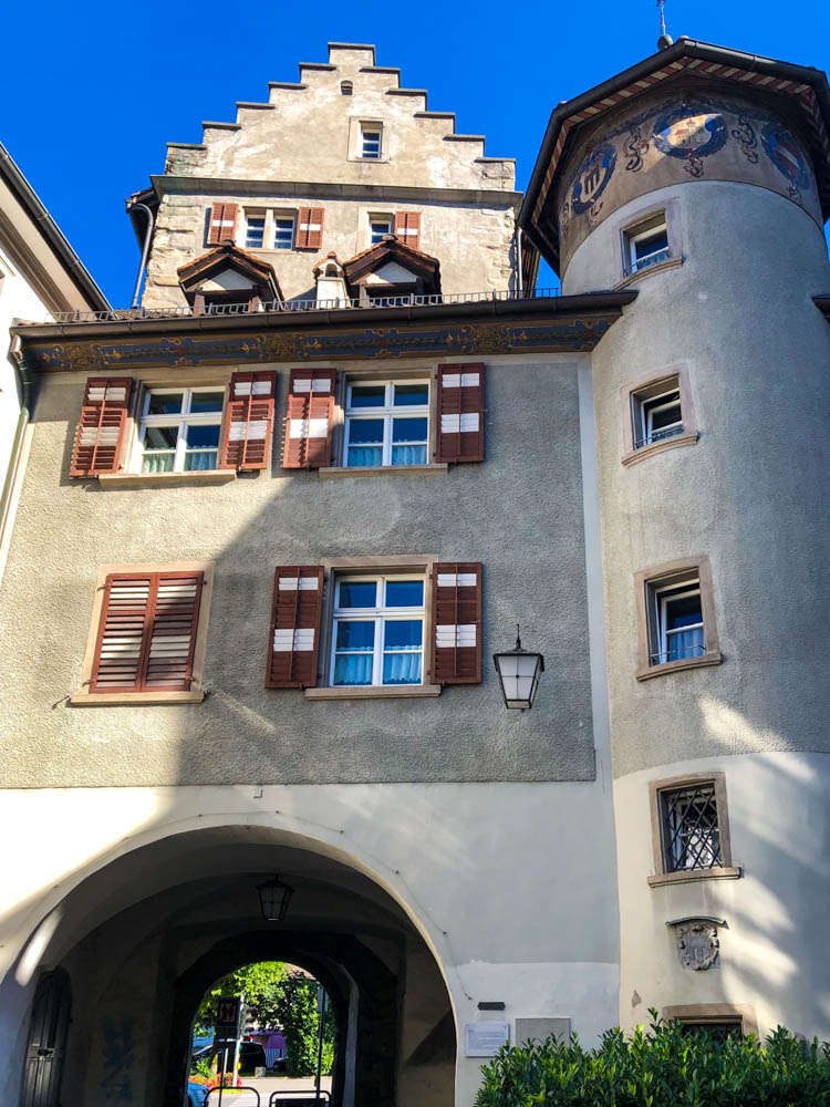 Mittelalterliches Stadttor in Feldkirch (Vorarlberg). Es sind ein Turm sowie ein Torbogen zu sehen. Der Himmel ist strahlend blau.