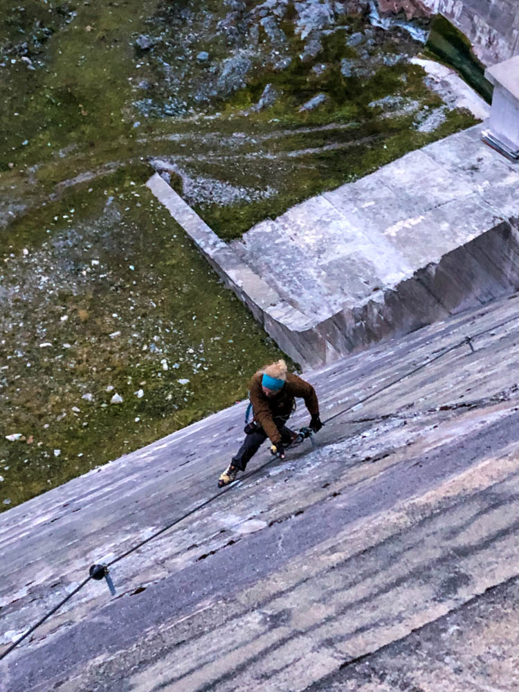 Julian im Silvretta Stausee Klettersteig, welcher eine Staumauer hinaufführt. Fotografie von oben auf Julian, der gerade in einer Querung ist.